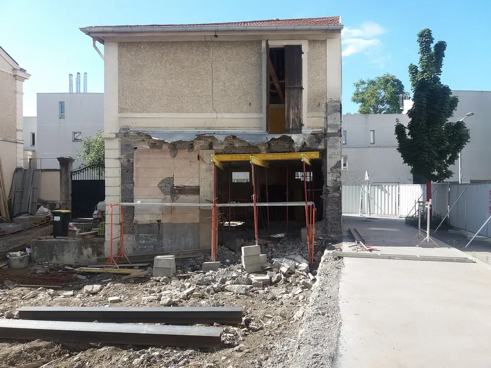 Rénovation d'une maison à Lyon, rez-de-chaussée ouvert et soutenu par des étais, gravats au sol et étage conservé au-dessus.