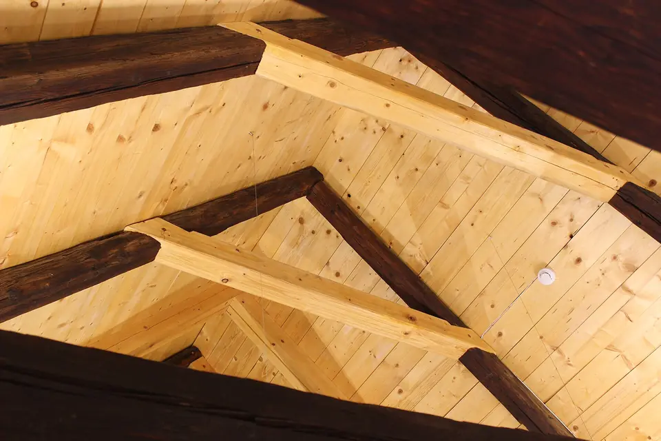 Aménagement de combles en cours dans un bâtiment de Prague, charpente ancienne renforcée et habillage neuf en lambris de bois clair.